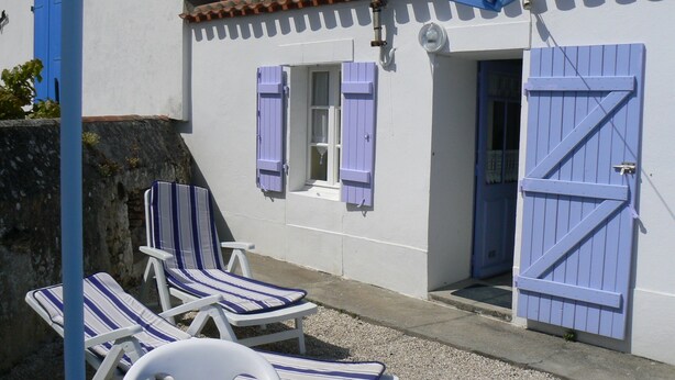 A building with a white exterior and blue shutters, a door, and a window. There are three white lounge chairs with blue and white striped cushions. - Renovated traditional fisherman's cottage 250 m from the beach (L'Épine)