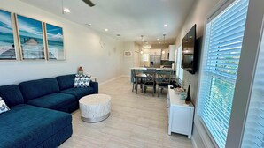 A modern living room with a dark blue sofa, a round coffee table, and a dining area with a table and chairs.