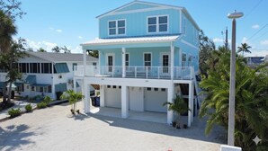 A two-story building with a balcony, numbered 244 and 240, surrounded by palm trees and a clear sky.