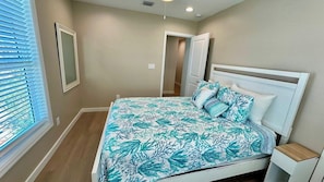 A bedroom with a bed, bedside table, and a window with blinds.