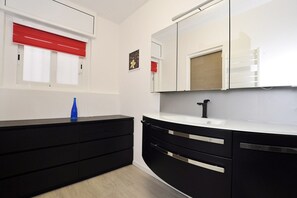 Ein modernes Badezimmer mit einem schwarzen Waschtisch, einer weißen Arbeitsplatte und einem großen Spiegel.