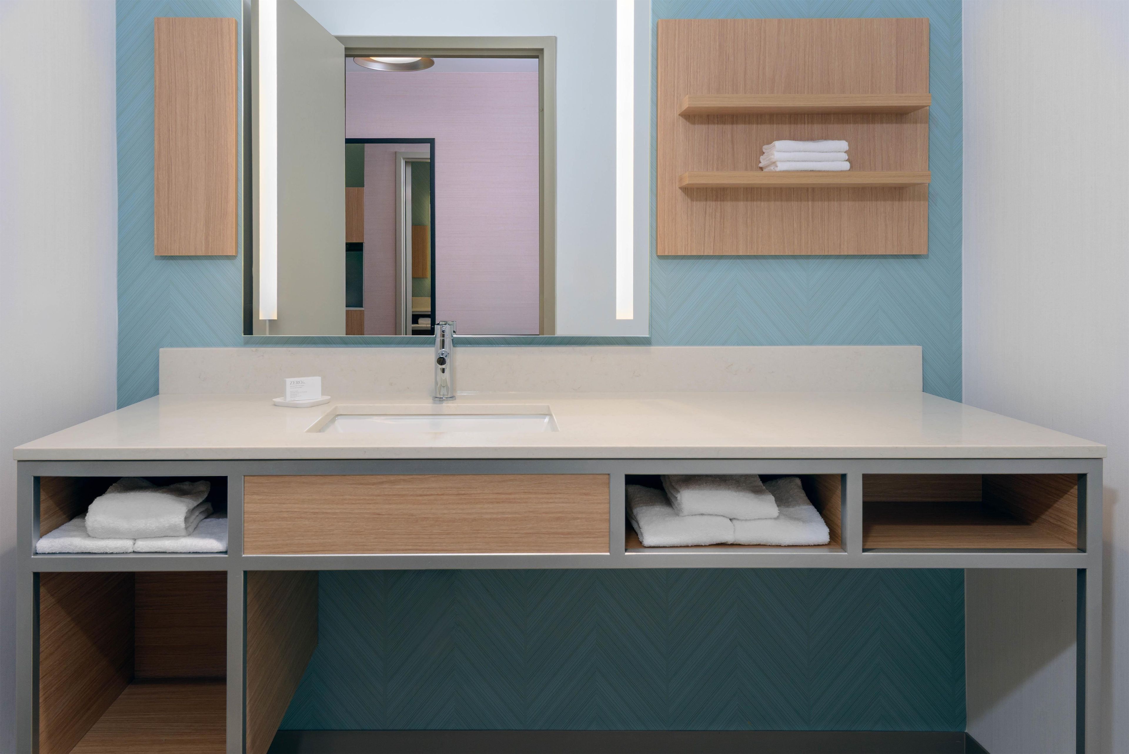 A bathroom with a white sink, a mirror, and wooden storage shelves.