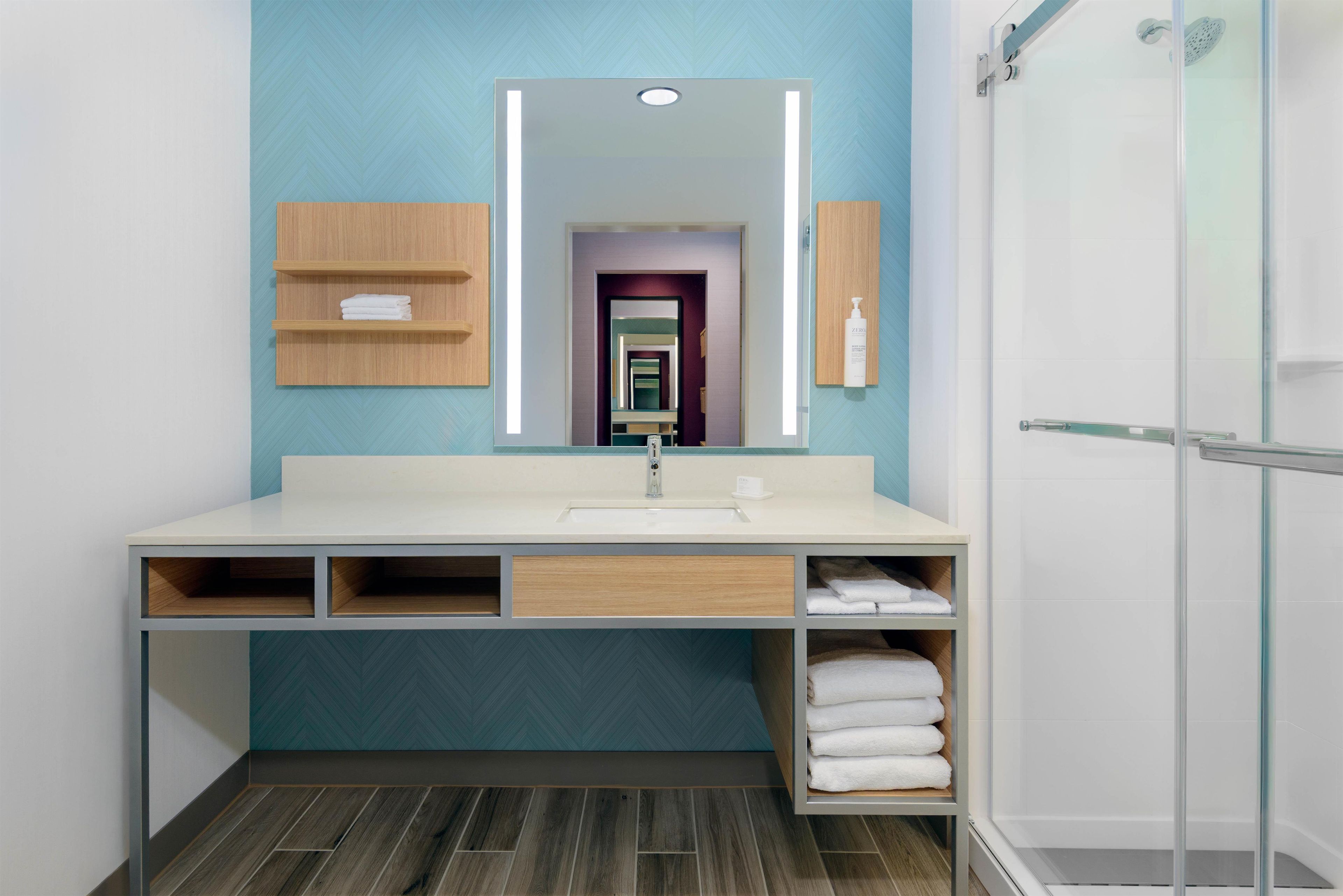 Un baño moderno con un espejo grande, un lavabo y una ducha.