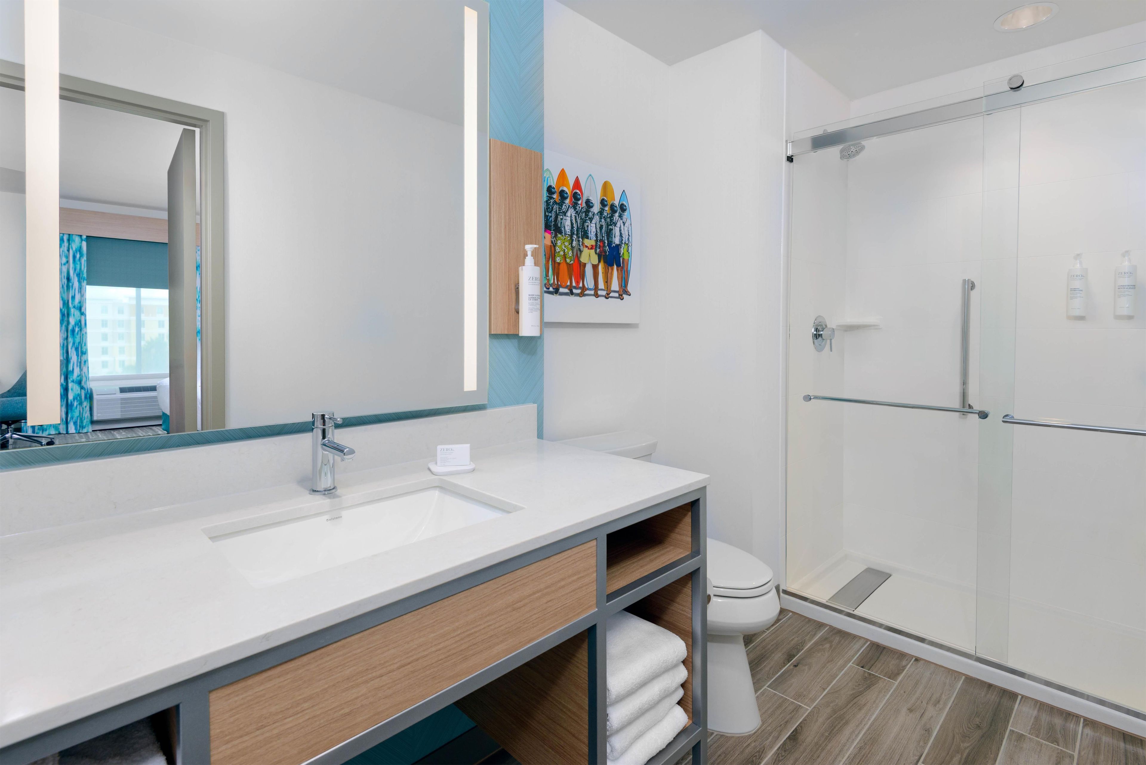 A modern bathroom with a large mirror, a sink, a toilet, and a shower area.