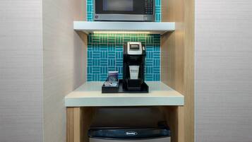 A compact kitchenette with a microwave, coffee machine, and a dishwasher.