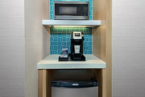Una kitchenette compacta equipada con microondas, cafetera y lavavajillas.