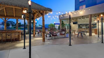 An outdoor patio area with seating arrangements, a bar, and a restaurant.
