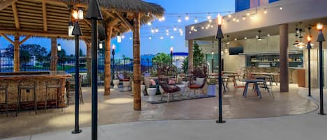 An outdoor patio area with seating arrangements, a bar, and a restaurant.
