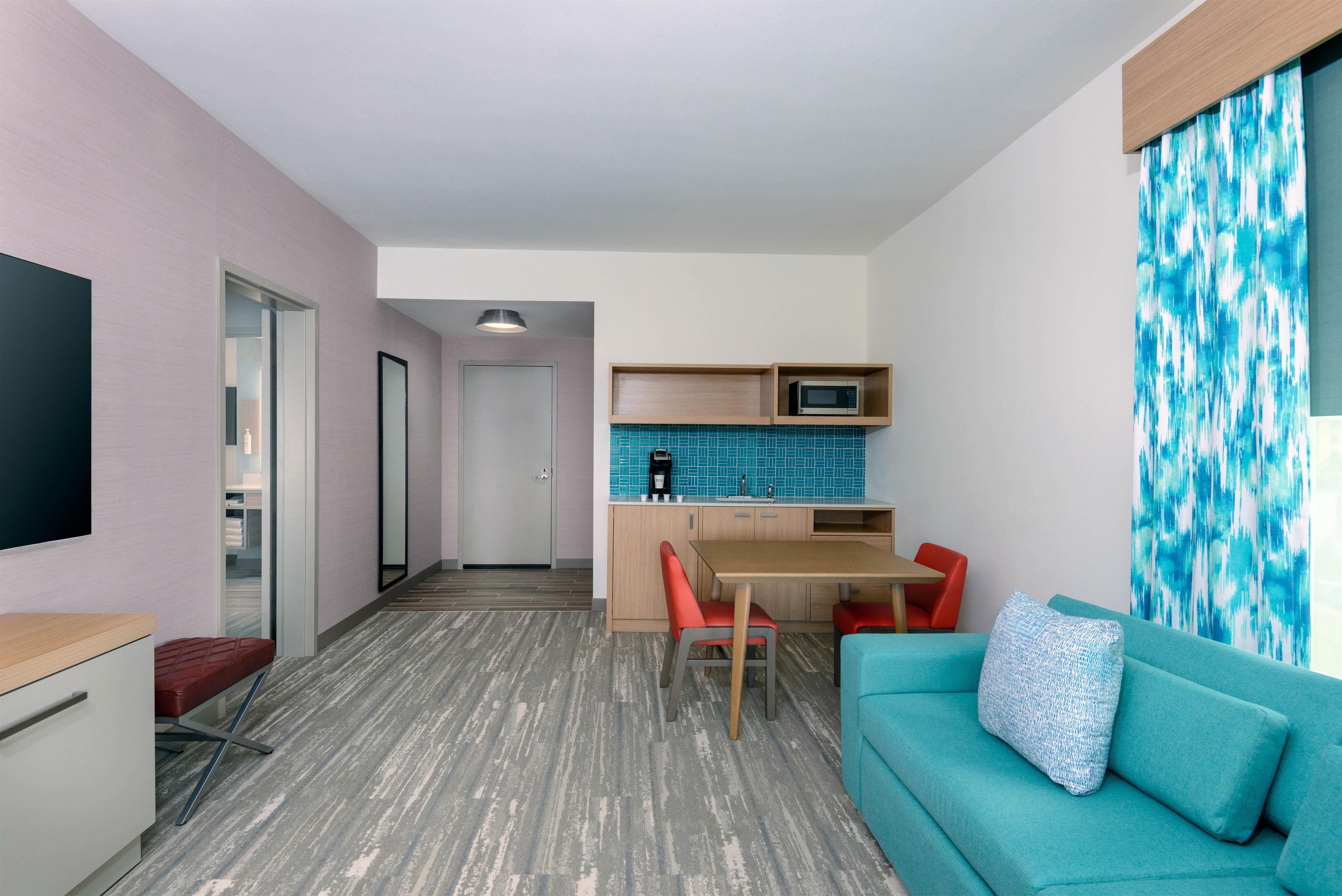 Un espacio habitable compacto con kitchenette, una zona de comedor y un área de estar con sofá y sillas.