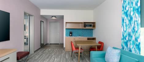Un espacio habitable compacto con kitchenette, una zona de comedor y un área de estar con sofá y sillas.