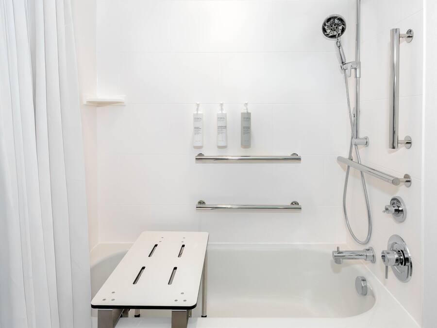 Un baño moderno con ducha a ras de suelo, cabezal de ducha manual, manguera de ducha manual y alcachofa de ducha manual.