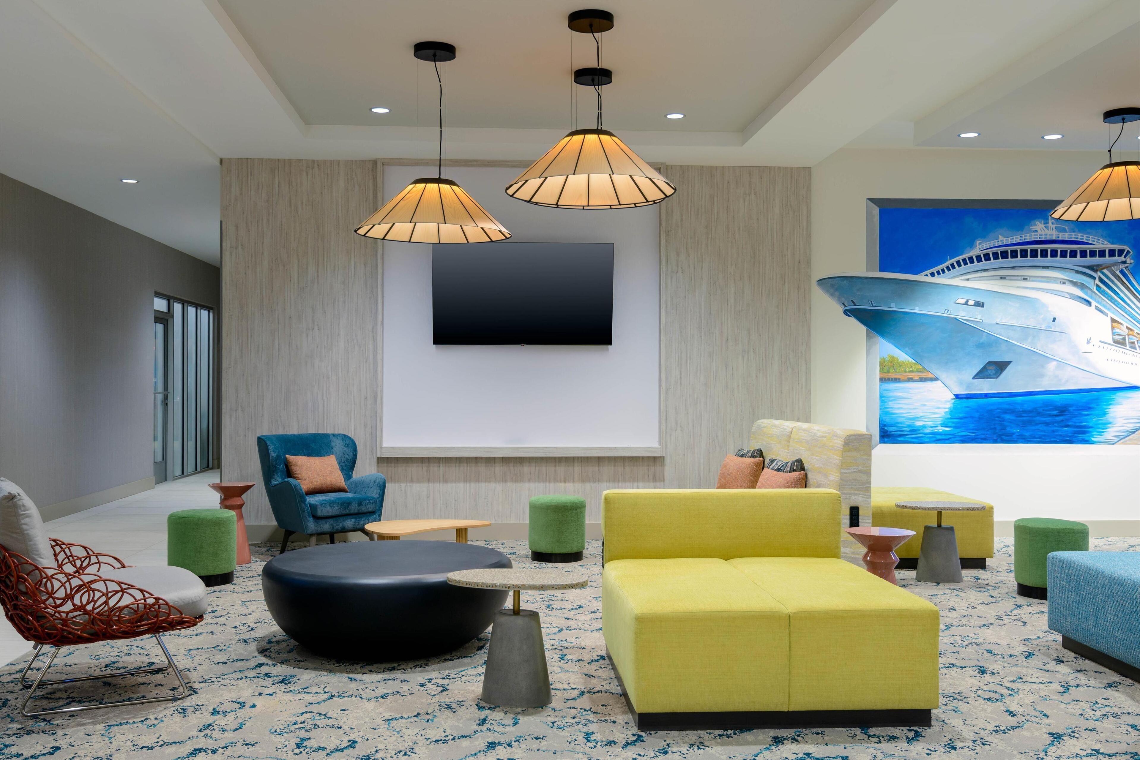 A modern lounge area with a large flat-screen TV, comfortable seating, and a nautical-themed mural.