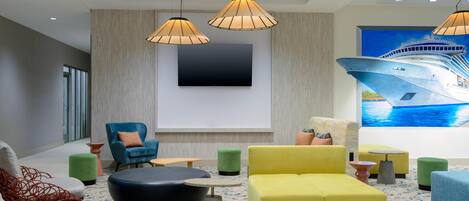 A modern lounge area with a large flat-screen TV, comfortable seating, and a nautical-themed mural.