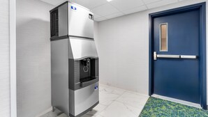 A commercial refrigerator with a water dispenser, a blue door, and a patterned rug.