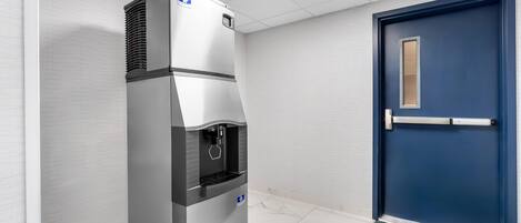 Un refrigerador comercial con dispensador de agua, puerta azul y alfombra estampada.