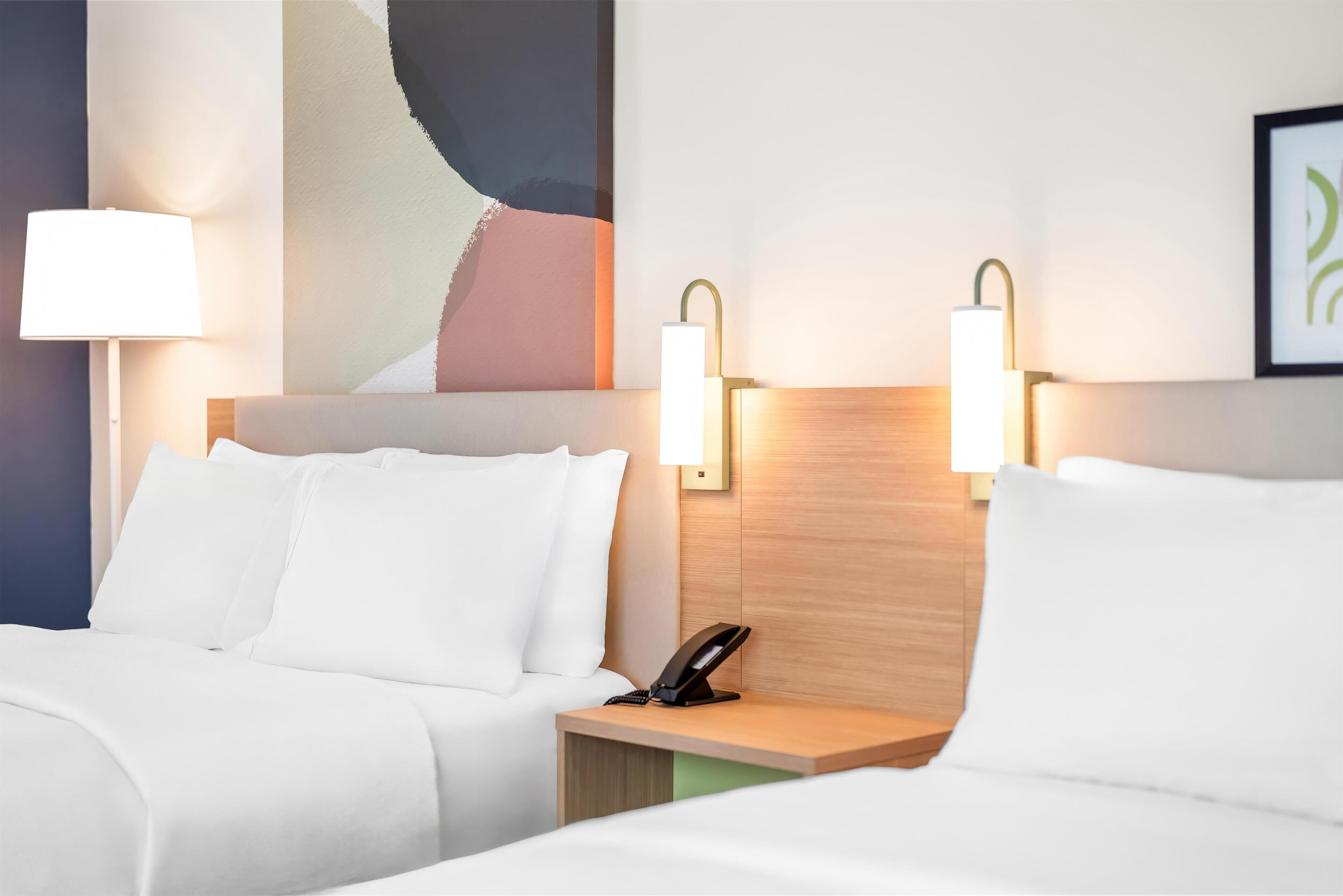A hotel room with two beds, a wooden headboard, and bedside lamps.