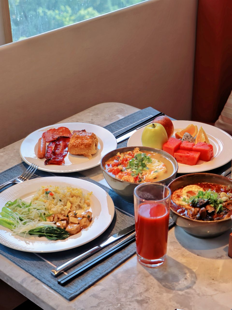 A table with various dishes including fried rice, soup, and fruit.
