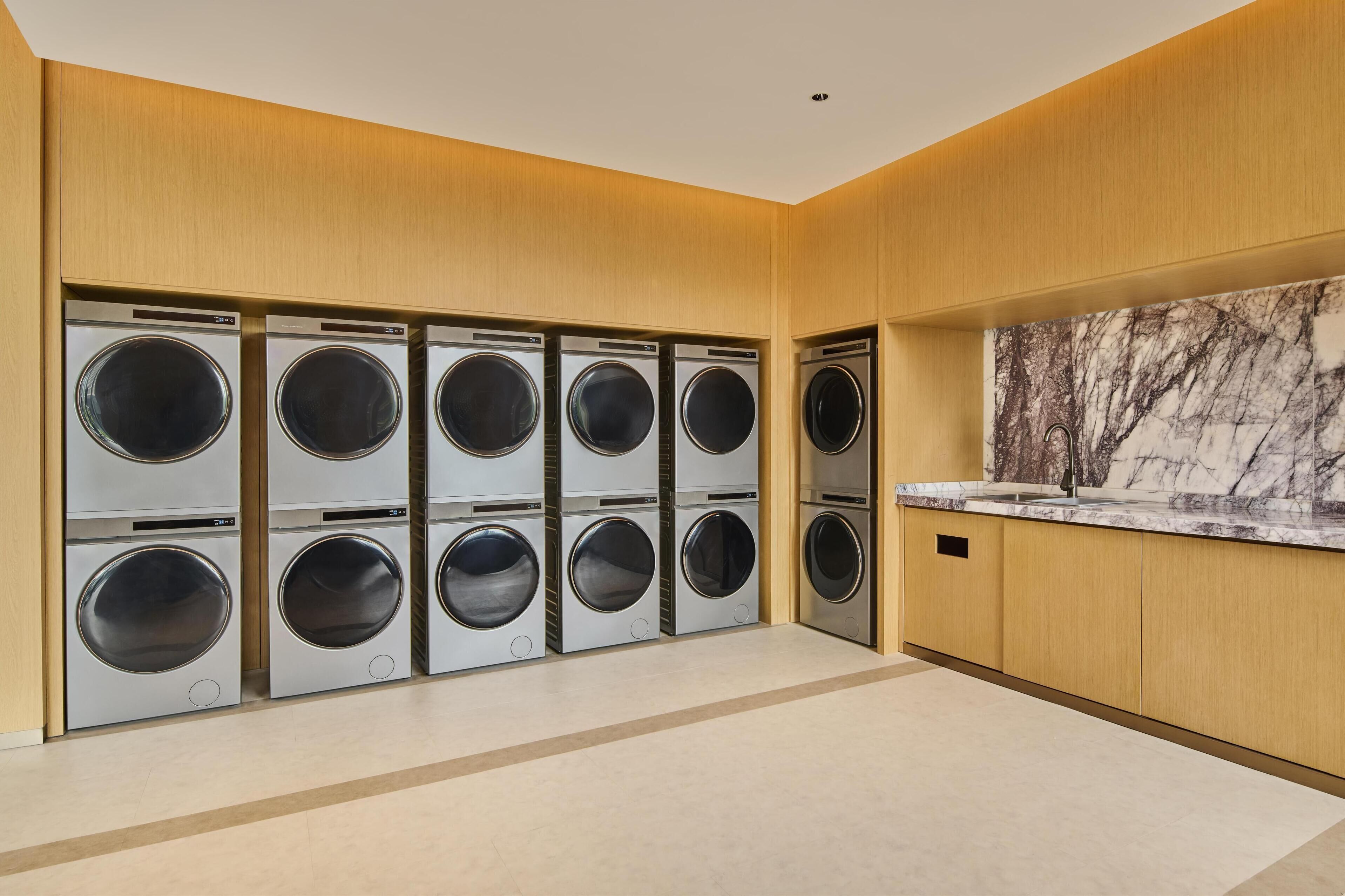 A modern laundry room with multiple washing machines and a marble countertop.