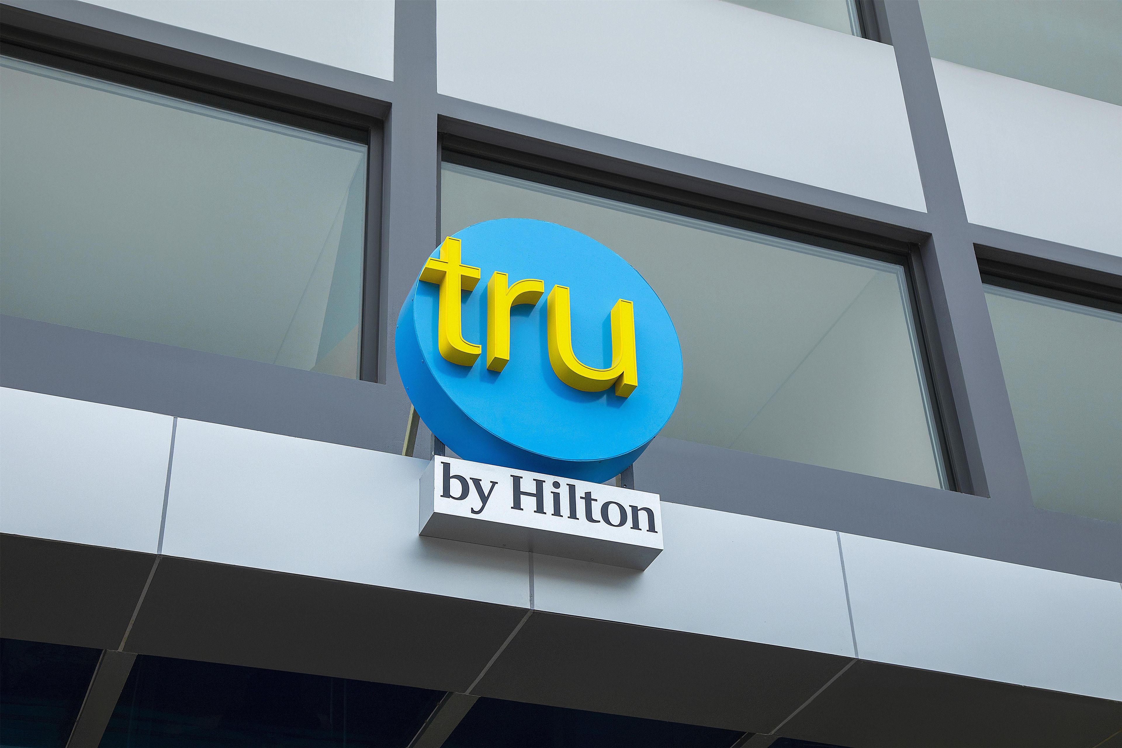 A building with a blue sign that reads 'tru by Hilton'.