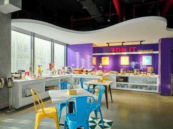 A breakfast area with purple walls, a counter with food items, and blue and yellow chairs.