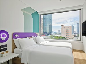 Une chambre d’hôtel moderne avec deux lits, une grande fenêtre donnant sur la ville et un mur d’accent de couleur violette.