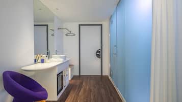 A modern bathroom with a white sink, mirror, and purple chair.