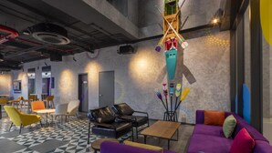A modern lounge area with a geometric patterned floor, leather and fabric seating, and a unique hanging installation. - Tru By Hilton Da Nang City Centre (Da Nang)