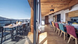 A dining area with a view of snow-capped mountains, wooden ceiling, and modern furnishings.