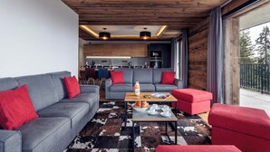 A modern living room with a grey sofa and red cushions, a coffee table with a bottle and glasses, and a cowhide rug.