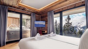 A bedroom with a large bed, a TV, and a view of mountains.