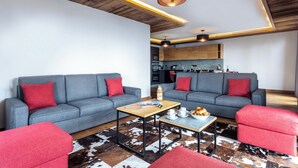 Ein modernes Wohnzimmer mit grauen Sofas, roten Kissen, einem Holztisch und einem Cowhide-Teppich.