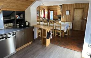 Una cocina compacta con una mesa y sillas de madera, lavavajillas y un pequeño comedor.