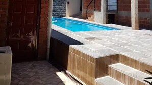 Un edificio de dos pisos con piscina, techo de madera y fachada de ladrillo.