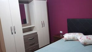 Un dormitorio con una cama, un armario y una mesita de noche.