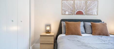 Un dormitorio con cama, mesita de noche y decoración en la pared.