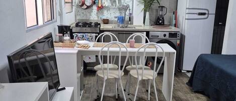 A compact kitchen with a dining area, white cabinetry, and a built-in refrigerator.