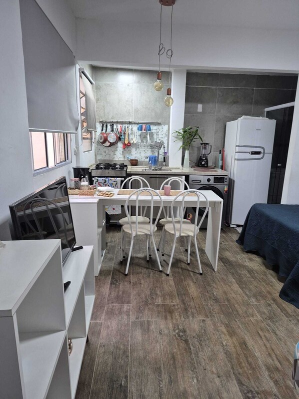 A compact kitchen with a dining area, white cabinetry, and a built-in refrigerator.