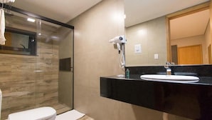 A modern bathroom with a glass shower enclosure, a black countertop sink, and a mirror above it. - Adria Premium Hotel (Guarapuava)