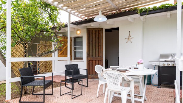 An outdoor patio with a covered seating area, a grill, and a wooden door. - Monolocale Elena - Quartu Sant'e... (Quartu sant'elena)