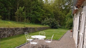 A patio with a white metal table and chairs, surrounded by a gravel path and a stone wall. - 4* gîte 15 minutes from Puy du Fou with heated swimming pool (Mortagne-sur-Sèvre)