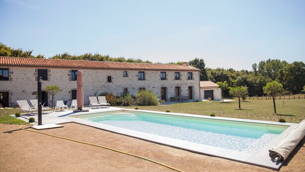 A pool area with lounge chairs, a building with a tiled roof, and a clear sky. - 4* gîte 15 minutes from Puy du Fou with heated swimming pool (Mortagne-sur-Sèvre)