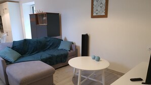 A living room with a sofa, a small round table, and a television. - 4* gîte 15 minutes from Puy du Fou with heated swimming pool (Mortagne-sur-Sèvre)