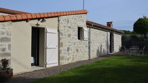 A stone building with a tiled roof, a door, and a small window. - 4* gîte 15 minutes from Puy du Fou with heated swimming pool (Mortagne-sur-Sèvre)