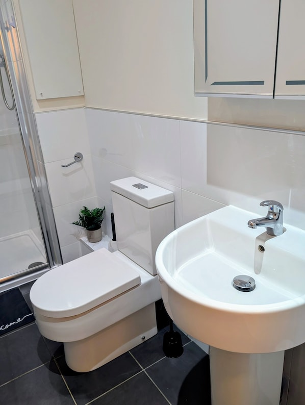 A modern bathroom with a toilet, sink, and shower. - Upperhead Row Apartment (Huddersfield)