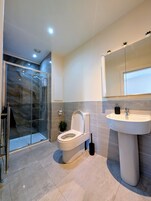 Apartamento superior, vistas a la ciudad | Baño | Ducha, artículos de higiene personal gratuitos y secador de pelo