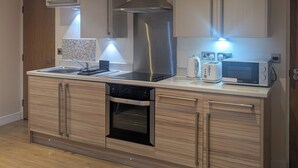A modern kitchen with a central island, built-in oven, microwave, and toaster. - Upperhead Row Apartment (Huddersfield)