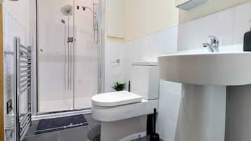 Et moderne badeværelse med bruser, toilet og vask.