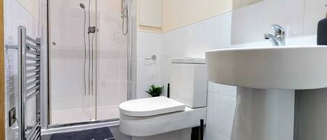 A modern bathroom with a shower, toilet, and sink.