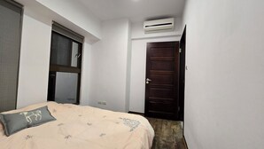 A bedroom with a bed, a window, an air conditioner, and a door. - Cozy 1-bedroom apartment with AC, WiFi in excellent Taipei (Taipei)