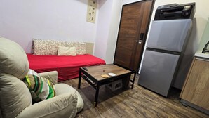 A compact room with a bed, a sofa, a small table, and a refrigerator. - Cozy 1-bedroom apartment with AC, WiFi in excellent Taipei (Taipei)